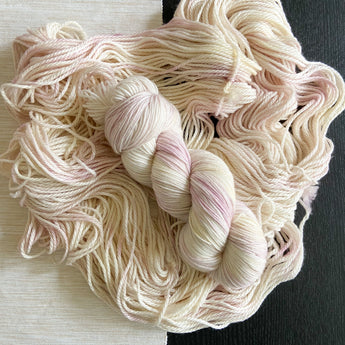 a skein of hand dyed yarn laid on top of more yarn