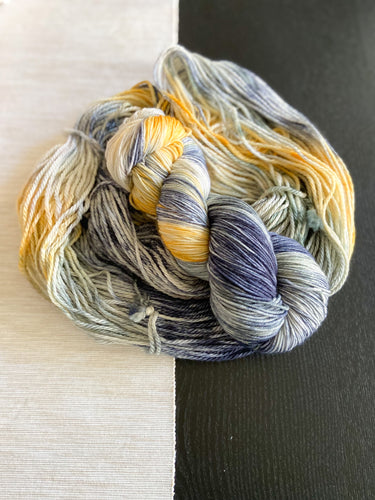 A skein of hand dyed yarn laid on top of more hand dyed yarn