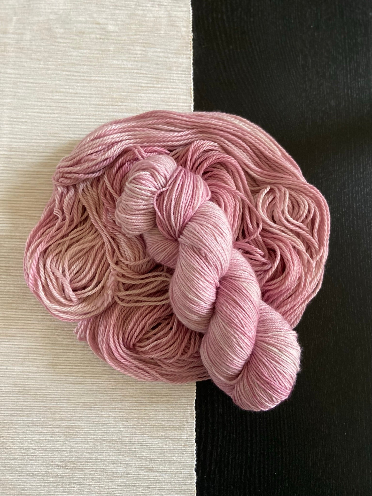 a skein of hand dyed pink yarn laid on top of more yarn