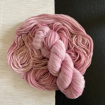 a skein of hand dyed pink yarn laid on top of more yarn